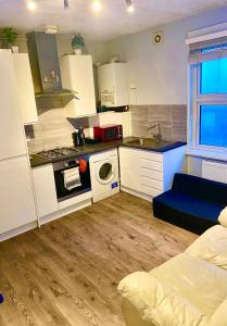 伦敦Flat in Tower Bridge的小厨房配有白色橱柜和蓝色沙发