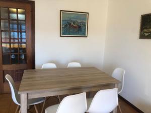 拉科萨Piso centro de Raxò的一间带木桌和白色椅子的用餐室