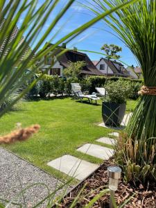 康斯坦茨Tolle Ferienwohnung Le Gira mit eigenem Garten的一个带草坪和椅子的花园以及棕榈树