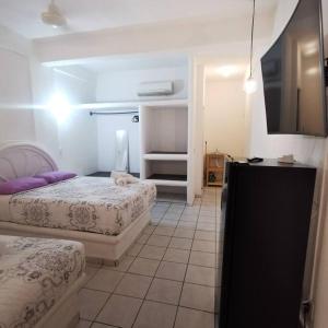 锡瓦塔塔内霍Lovely studio apartment with balcony AC & wi-fi, minutes from downtown!的一间卧室配有两张床和一台平面电视