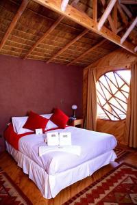 圣佩德罗·德·阿塔卡马波布拉多奇麦尔酒店的一间卧室配有一张带红色和白色枕头的大床