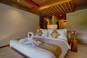 乌布Kastara Resort的卧室配有带毛巾的大型白色床