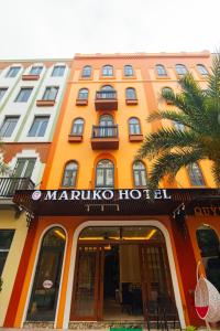 下龙湾Maruko Hạ Long Hotel的一座大型橙色建筑,上面标有酒店标志