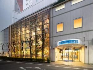 东京ART HOTEL Nippori Lungwood的一座大型玻璃建筑,前面是商店