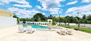 伊萨马尔Hotel Quinta Izamal的一个带四把椅子的游泳池和一个泳池景泳池