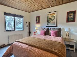 丁诺高原Snow Gums Apartment 4, alpine-getaways的卧室配有一张带粉红色枕头的大床