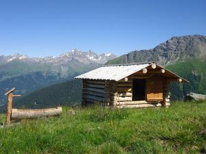 MalmigiuerTgamon Somtgant mit Glasdach的山丘上的小木屋,背景是山脉