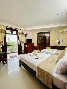顺化Nam Phương Riverside Villa的一间卧室设有两张床、一张桌子和一个窗口。
