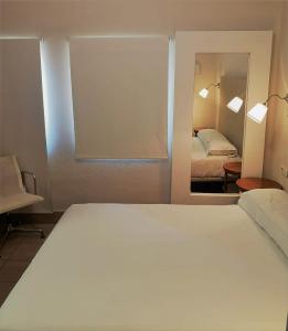 阿尔卡拉德瓜代拉奥罗马纳酒店的卧室配有一张白色大床和镜子