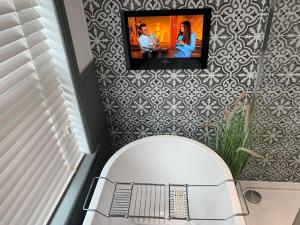 斯坦福德Luxury House, central Stamford with parking的一间带卫生间的浴室,墙上配有电视。