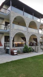 沃尔沃罗Aegialis Apartments (Dimitros)的一座建筑,前面有拱门和长凳