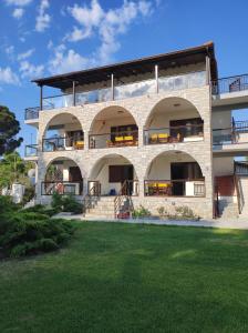 沃尔沃罗Aegialis Apartments (Dimitros)的一座大型砖砌建筑,设有阳台和草坪