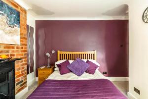 约克Camaraderie Guest House的一间卧室设有紫色的墙壁和一张带紫色枕头的床