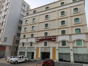 马斯喀特Al Ghubrah Plaza Hotel的停在大楼前的白色卡车