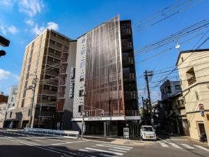 京都HOTEL LiVEMAX Kyoto Nijojo-kita的城市街道上一座高大的建筑,有车