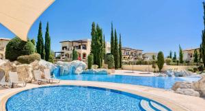 库克里亚Pool side ground floor apartment BF02 - Theseus Village, Aphrodite Hills Resort的度假村的游泳池,带椅子和树木