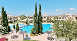 库克里亚Pool side ground floor apartment BF02 - Theseus Village, Aphrodite Hills Resort的度假村设有一个种有树木和遮阳伞的大型游泳池
