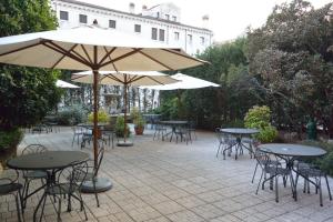 威尼斯贝里亚缇酒店的一个带桌椅和遮阳伞的户外庭院。