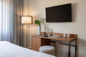 莱里奇多利亚公园酒店的酒店客房设有一张桌子、一台电视和一张床