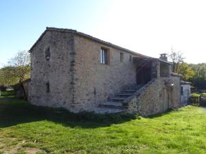 BlandasGîte de Navacelles的一座古老的石头建筑,在田野上设有楼梯