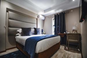哈博罗内卡皮塔尔旅馆的一间卧室配有一张带蓝色毯子的大床