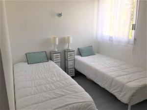 佩罗斯-吉雷克Appartement Perros-Guirec, 2 pièces, 4 personnes - FR-1-368-165的白色墙壁客房的两张床