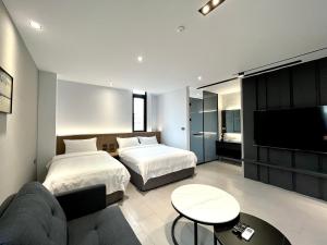 马公澎湖好思包栋公寓的一间带两张床、一张沙发和一台电视的卧室