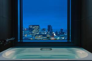 大阪The Royal Park Hotel Iconic Osaka Midosuji的浴缸以及市景窗户