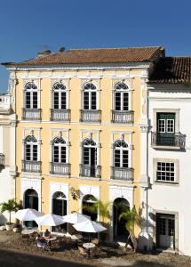萨尔瓦多巴伊亚别墅酒店的前面有桌子和遮阳伞的黄色建筑