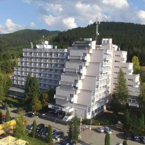 科瓦斯纳Hotel Montana - Covasna的一座白色的大建筑,前面设有停车场