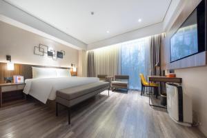 深圳深圳南山海岸城亚朵X酒店的一间卧室配有一张床、一张书桌和一台电视