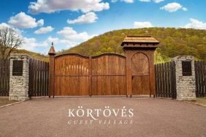 VîrghişKörtövés Guest Village的一个大木门,上面有读卡洛斯客村的标志