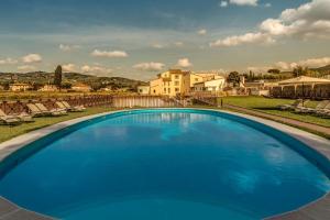 佛罗伦萨Hotel Mulino di Firenze - WorldHotels Crafted的一座大型蓝色游泳池,后面有一座房子