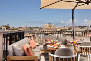 罗马Hotel L'Orologio Roma - WTB Hotels的庭院配有桌椅和遮阳伞。