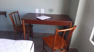 纳塔尔Ilusion Flat -Natal的一张带两把椅子和一张床的木桌