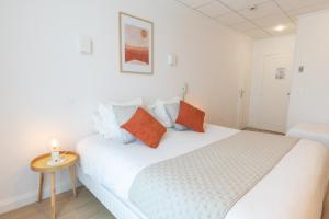 兰斯Hôtel Porte Mars Reims Gare Centre Arena的一间卧室配有白色的床和橙色和蓝色枕头