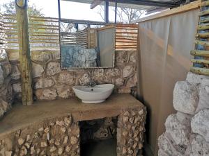 奥考奎约Etosha Village Campsite的石质浴室设有水槽和镜子