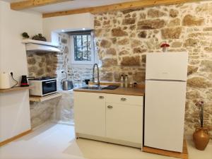 Ágios RókkosZaira's Apartment Corfu Town的厨房配有白色橱柜和石墙