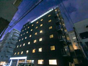 冈山HOTEL LiVEMAX Okayama West的一座高大的建筑,上面有灯