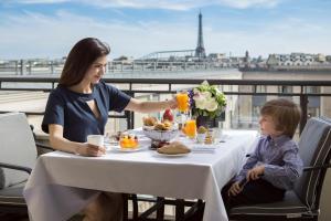 巴黎Hotel du Collectionneur的坐在餐桌旁吃饭的妇女和儿童