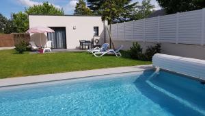 阿姆博斯La Chouette d'Amboise的庭院内的游泳池,配有两把椅子和一把遮阳伞