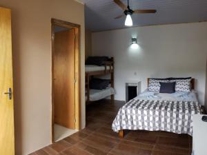 圣安东尼奥-杜皮尼亚尔Suites Chacara Madu的一间卧室配有一张床和吊扇