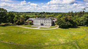 凯尔斯2 Bed Courtyard Apartment at Rockfield House Kells in Meath - Short Term Let的绿色田野上白色大房子的空中景色