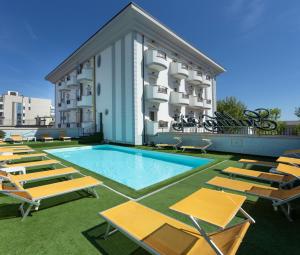 里米尼加丽雅皇宫酒店的一座带躺椅的游泳池和一座建筑