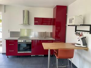 ScherwillerGite Au sauna de l’Aubach的厨房配有红色橱柜和木桌