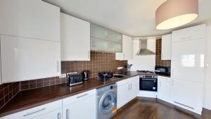 阿伯丁Orange Apartments Bothwell Road的厨房配有白色橱柜、洗衣机和烘干机