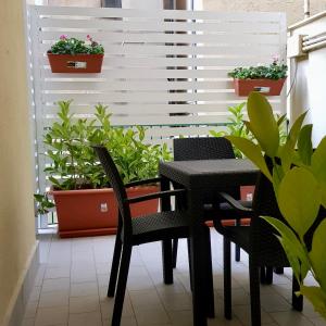 巴勒莫Residence D'azeglio的阳台配有桌椅和盆栽植物