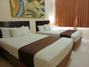 比亚埃尔莫萨HOTEL VILLA MARGARITAS的酒店客房设有两张床,墙上挂有绘画作品
