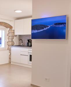 木洛希尼Apartment House Bucul的一间厨房,配有白色橱柜和墙上的电视