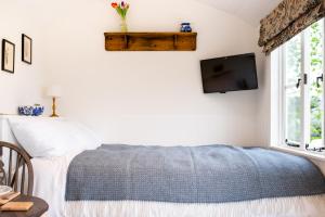 梅尔顿莫布雷Drift View Shepherds Hut的卧室配有一张床,墙上配有电视。
